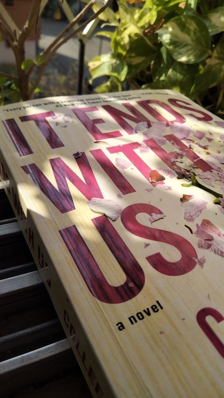 a close up of a wooden sign with writing on it and trees in the background