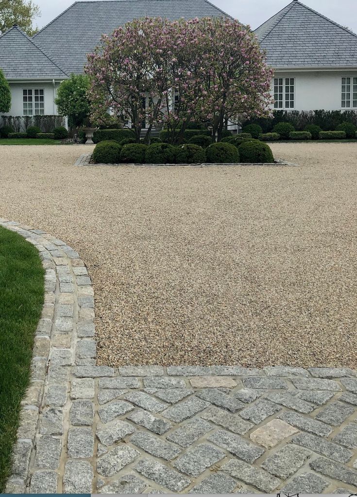 a gravel driveway in front of two white houses