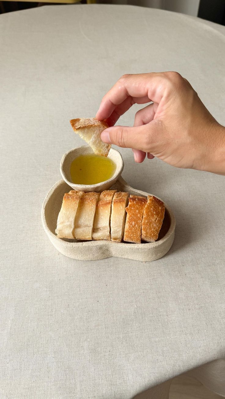 a person dipping some bread into a bowl