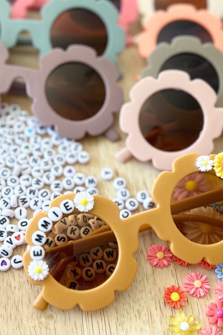 several pairs of sunglasses sitting on top of a wooden table next to flowers and letters