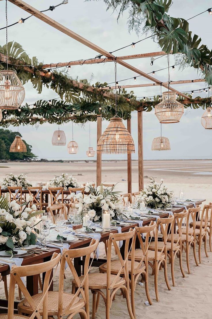 an outdoor dining area with wooden chairs and tables set up for a wedding reception on the beach