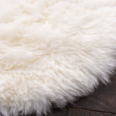 a white shaggy rug on top of a wooden floor