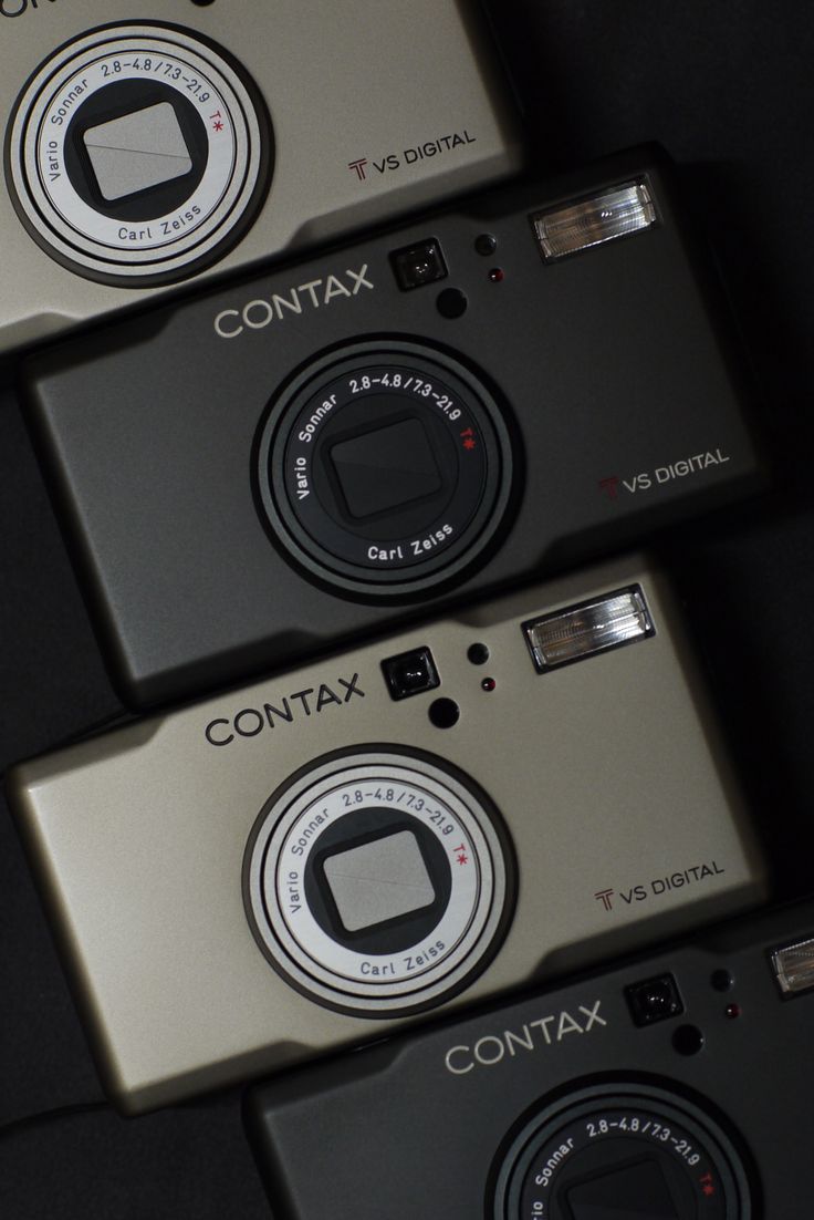 three cameras sitting next to each other on top of a black surface with the words contax printed on it