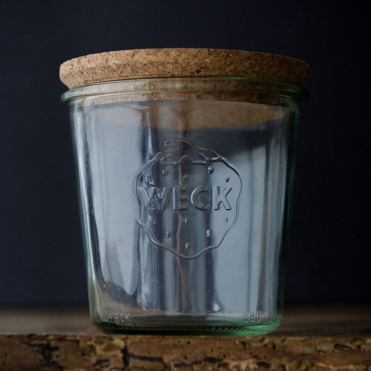 a glass jar sitting on top of a wooden table next to a cork covered lid