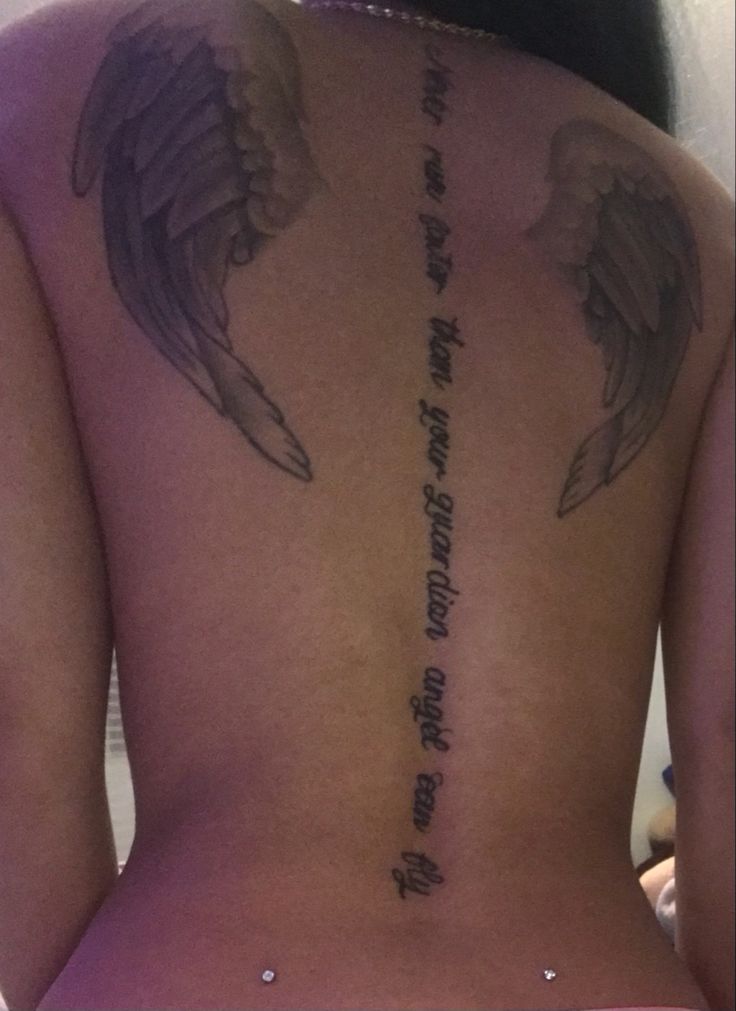 the back of a woman's body with angel wings and chinese writing on it