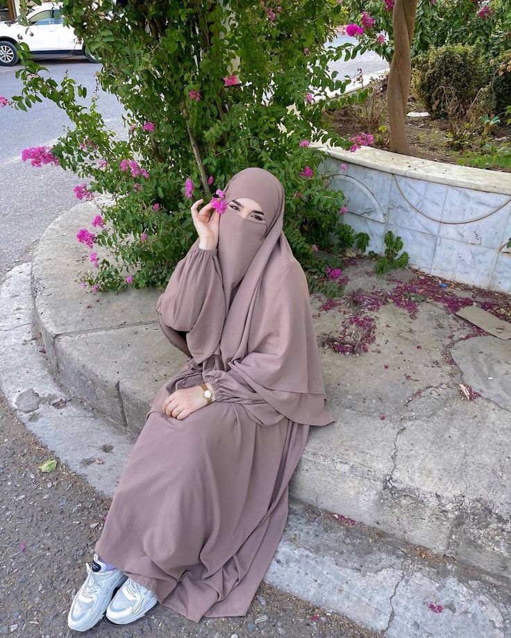 a woman in a hijab sitting on steps talking on her cell phone