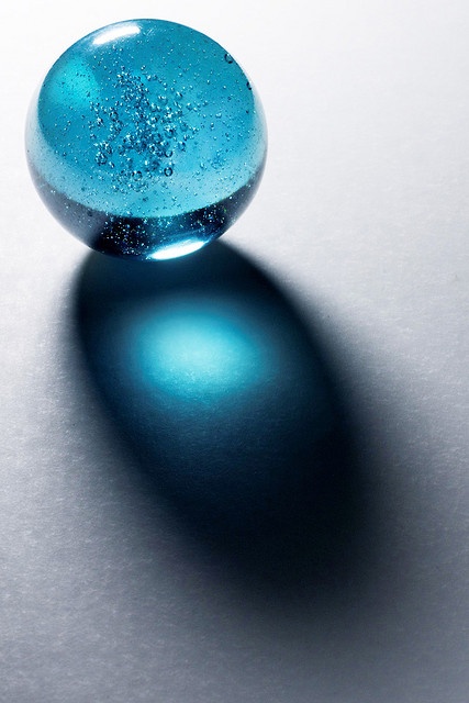 a blue ball sitting on top of a white table next to a black object with water droplets