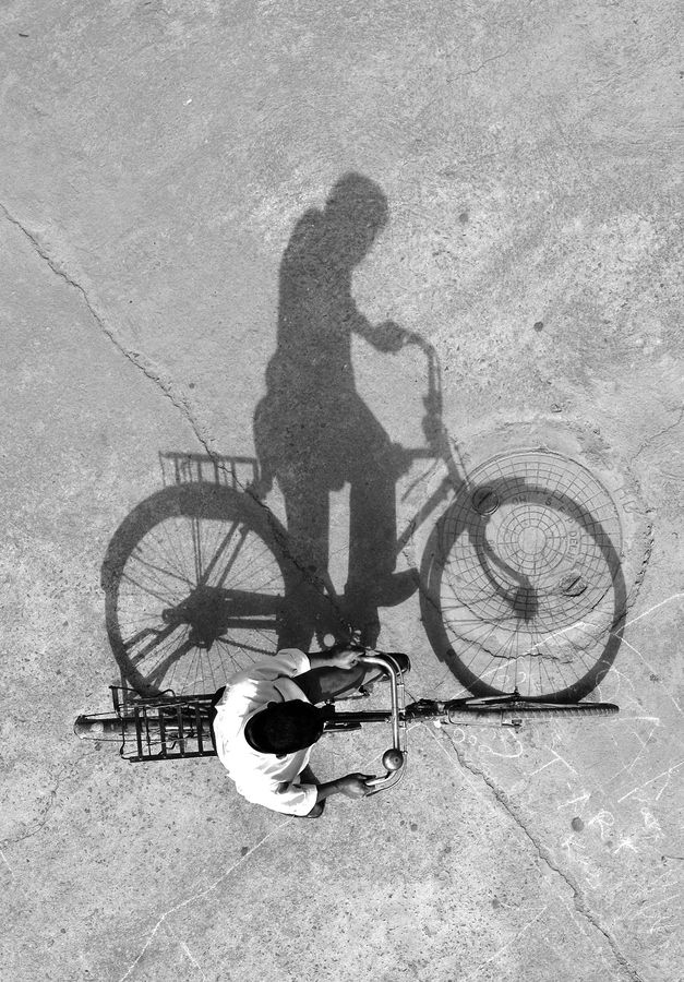 a shadow of a person riding a bike next to a basket on the ground,