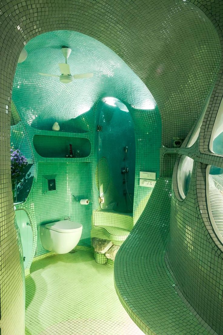 a bathroom with green tiled walls and flooring in the shape of an ocean wave