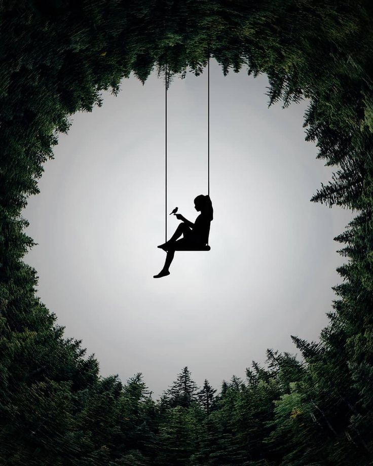 a woman sitting on a swing in the middle of a forest