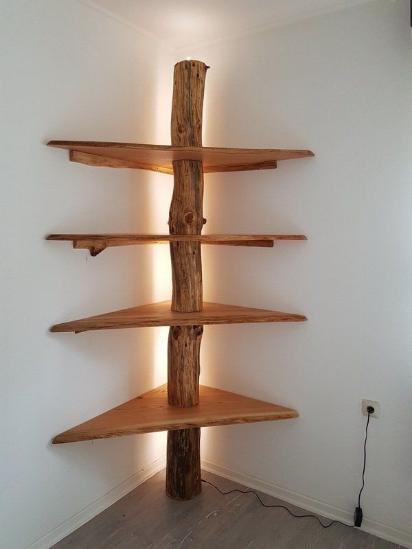 a tall wooden shelf sitting in the corner of a room next to a wall mounted light