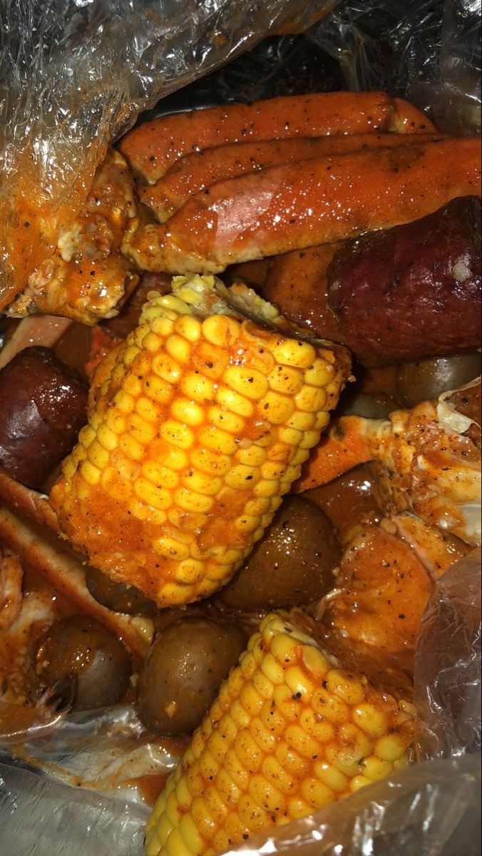 corn on the cob and sausages wrapped in plastic wrapper, ready to be cooked