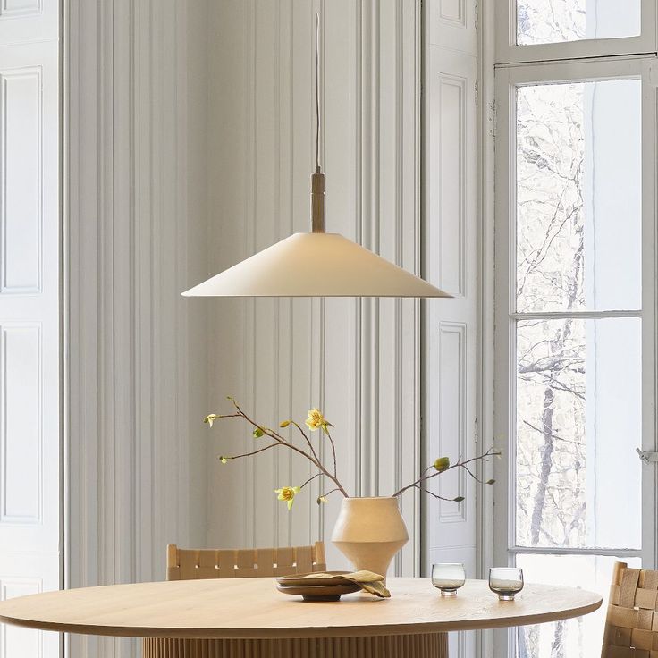 a dining room table with two chairs and a vase on the table next to it