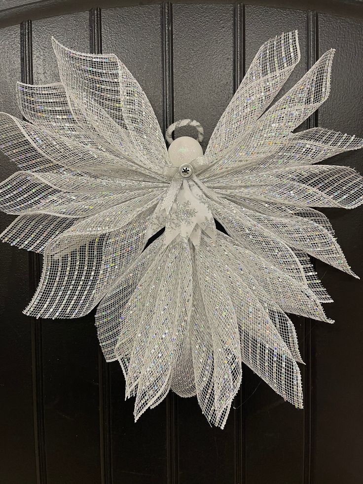 a door with a white mesh flower and leaves hanging from it's front door