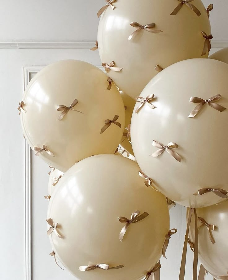 white balloons with bows on them in front of a door