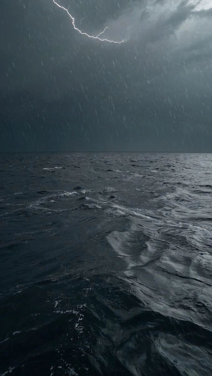 a storm is coming over the ocean and it appears to be raining with lightning in the sky