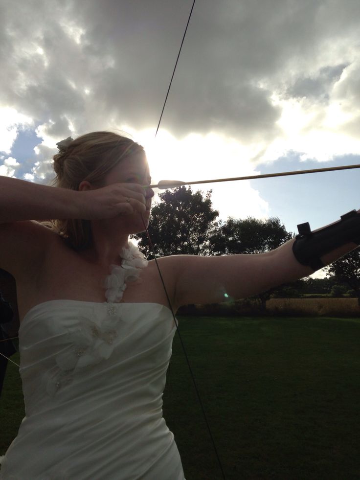 a woman in a white dress is holding her arm out to the sky with an arrow