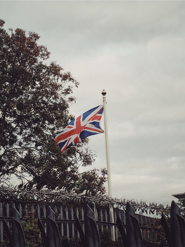 a british flag flying in the wind next to a fence