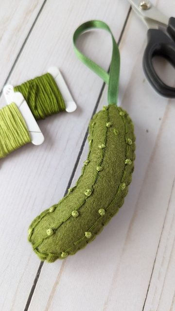 scissors and thread are sitting on the table next to a green object that looks like a cucumber