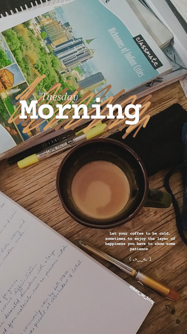 a cup of coffee sitting on top of a wooden table next to a notepad