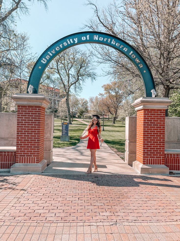 a woman in a red dress is standing under an arch that says university of montana