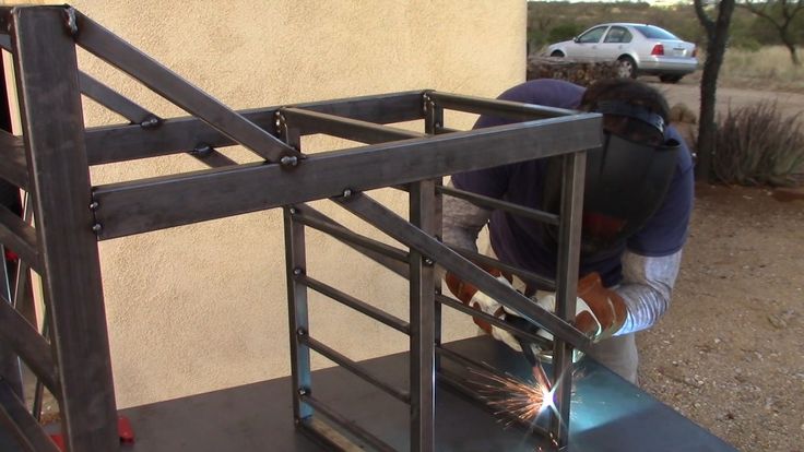 a man welding metal bars on the side of a building