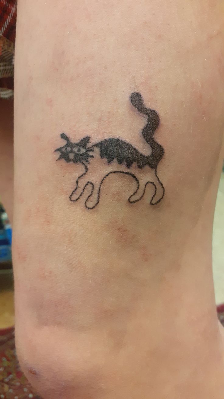 a small tattoo on the leg of a woman's lower body, depicting a cat