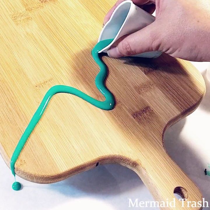 a person is using a roller to paint a wooden board with green tape on it