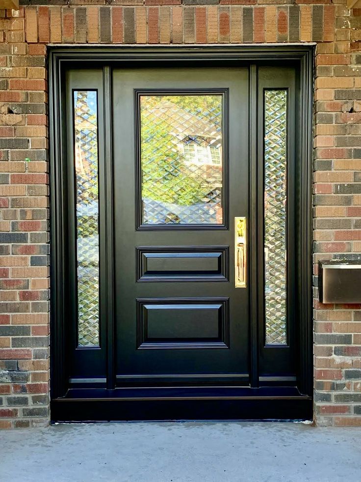 a black front door on a brick building with glass panels and sidelights in the window