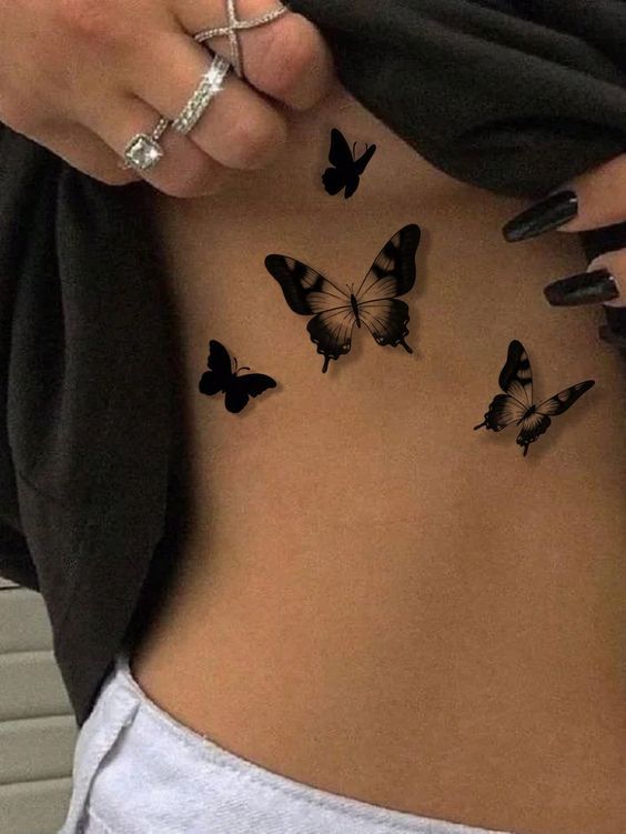 a woman's stomach with butterflies on the side and her hand holding it up