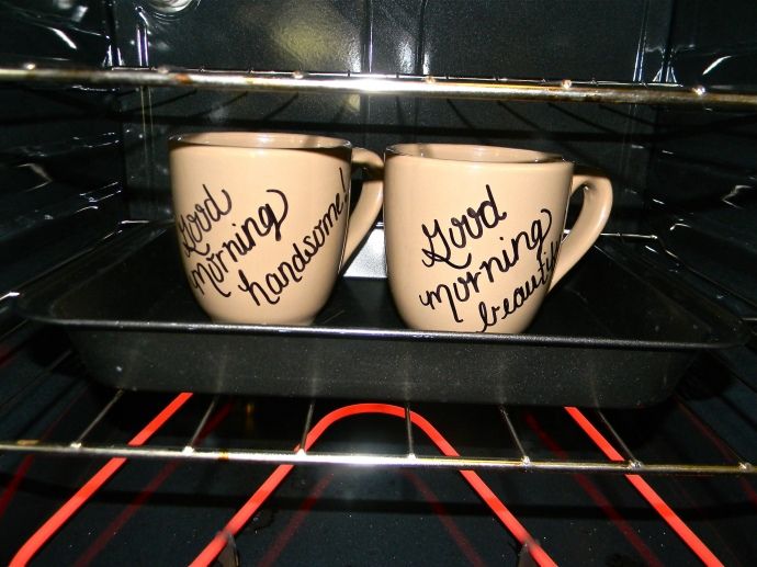 two coffee mugs with writing on them sitting in an oven