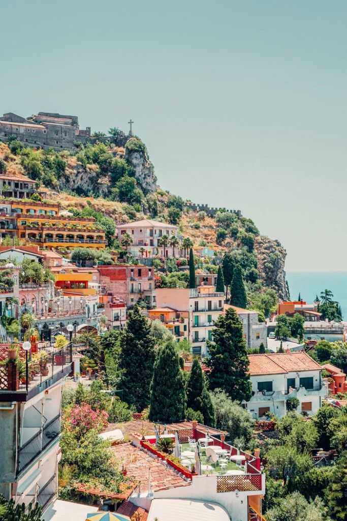 the city is on top of a hill with many buildings and trees in front of it