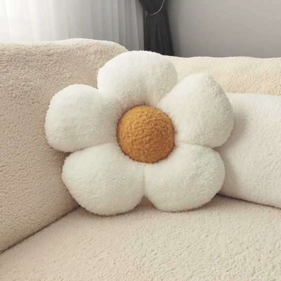 a white flower pillow sitting on top of a couch