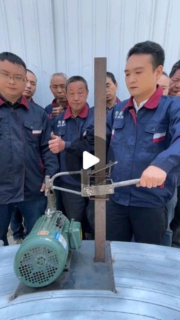 several men in blue uniforms are looking at an object on top of a metal barrel