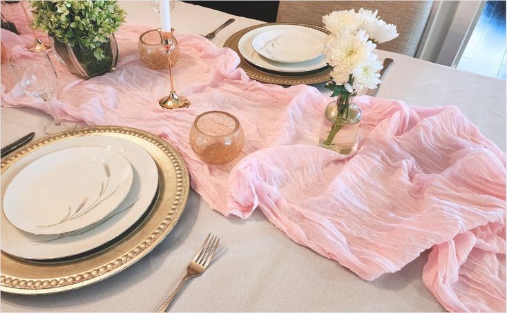 the table is set with plates, silverware and flowers