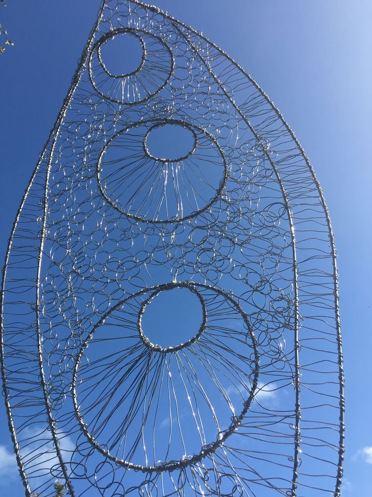 a metal sculpture with four circles on it's side and blue sky in the background