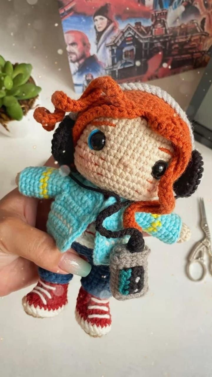 a crocheted doll is being held by someone's hand