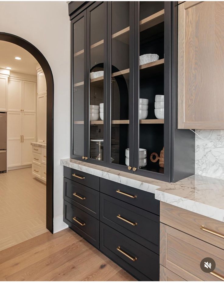 a kitchen with black cabinets and marble counter tops