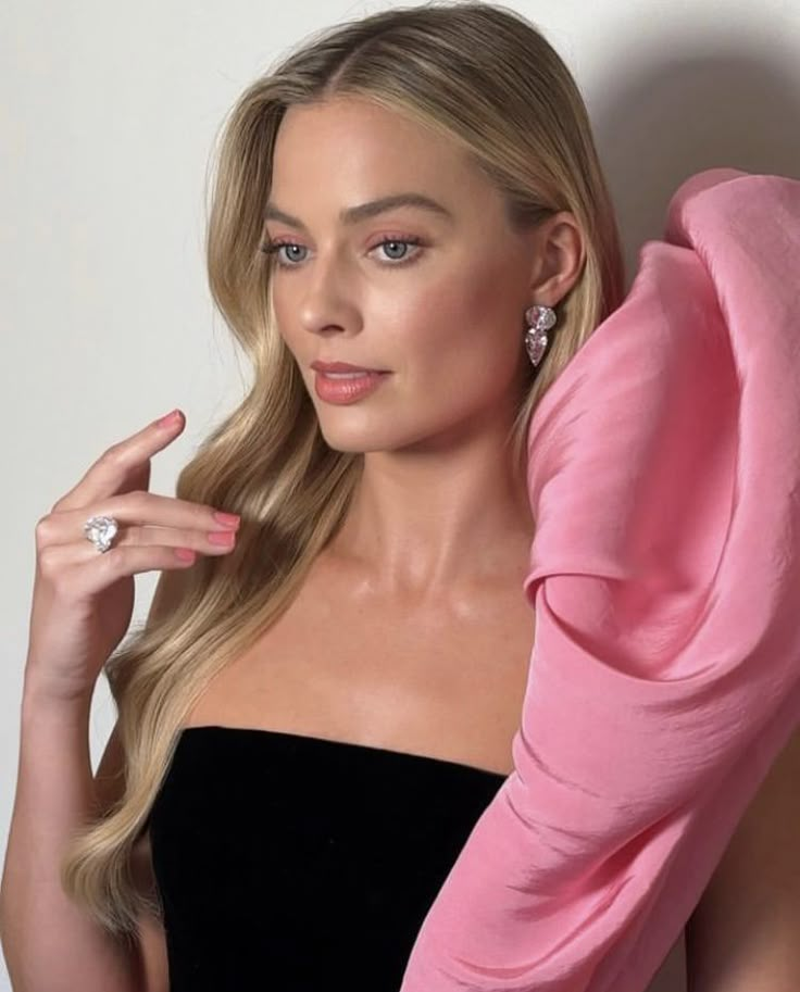 a woman in a black dress is holding her pink scarf over her shoulder and posing for the camera