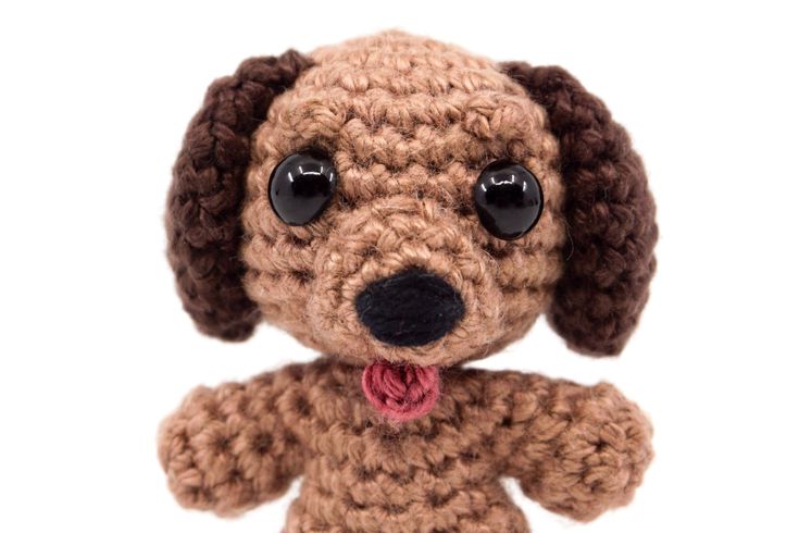 a crocheted dog with big eyes and a tongue sticking out from it's chest