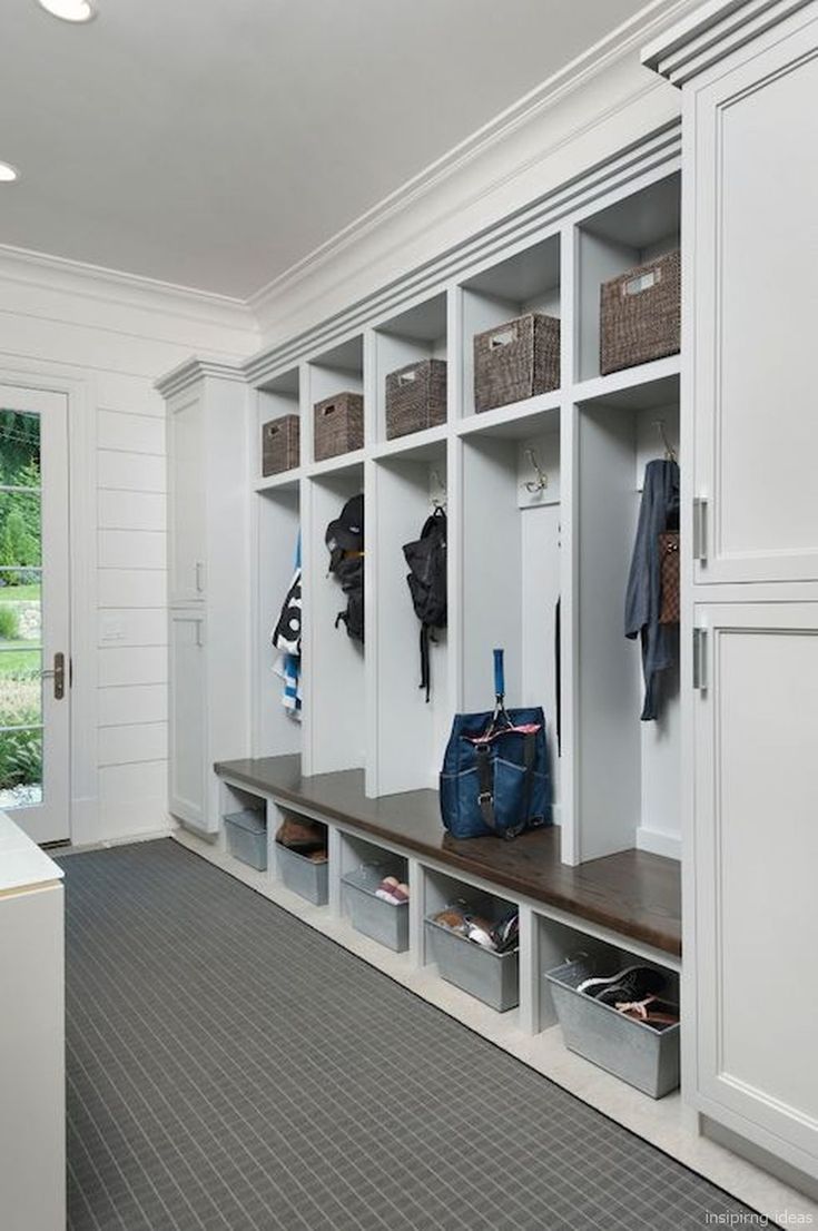 an organized mudroom with white cabinets and shelves filled with shoes, bags and purses