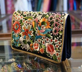 an embroidered purse sitting on top of a glass table