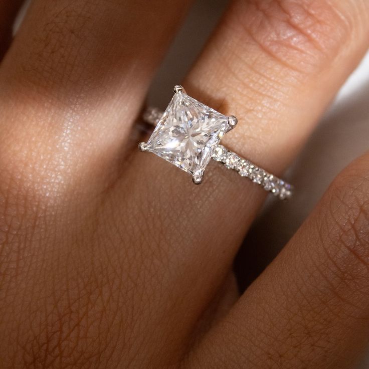 a woman's hand with a diamond ring on top of her finger and an engagement band