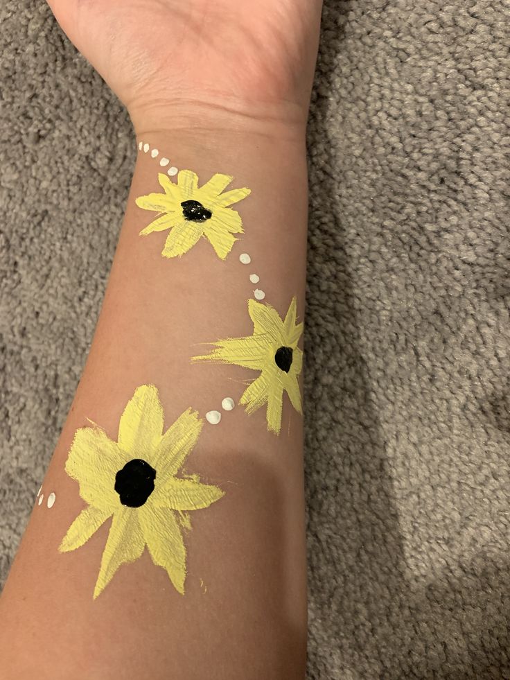 a person's arm with yellow flowers painted on it