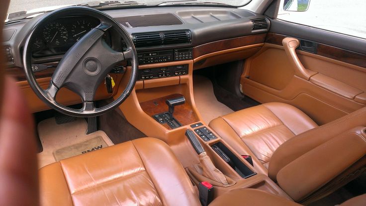 an interior view of a car with brown leather seats and steering wheel, including the center console