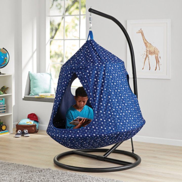 a little boy sitting in a blue hanging chair with white polka dot print on it