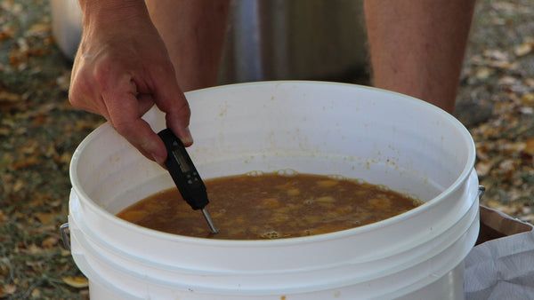 a person holding a knife in a bucket full of soup with another hand on the lid