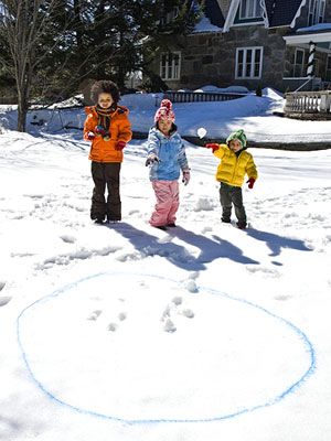 three children are standing in the snow near a circle