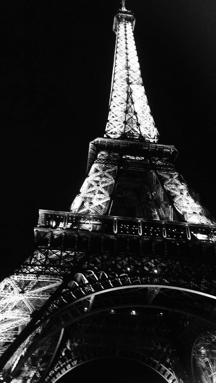 the eiffel tower lit up at night in black and white with lights on it