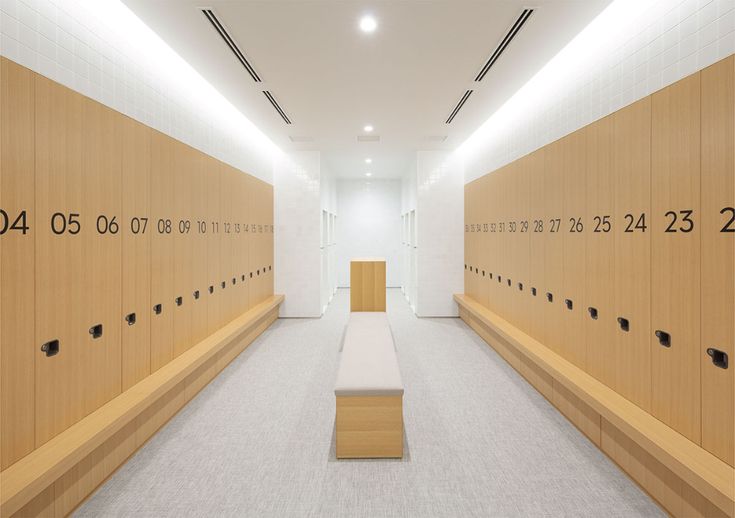 a long hallway with wooden lockers and numbers on the walls, along with benches